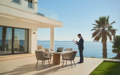 Casa de alquiler vacacional en la Costa del Sol con una persona revisando documentos en una mesa al aire libre frente al mar.